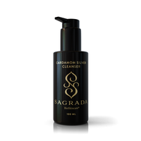 The Sagrada Cardamom Silver Cleanser by Sagrada BioSkincare comes in a 100 mL black pump bottle with gold logo and text. This gentle antioxidant-rich cleanser uses olive oil for deep purification and radiant skin.