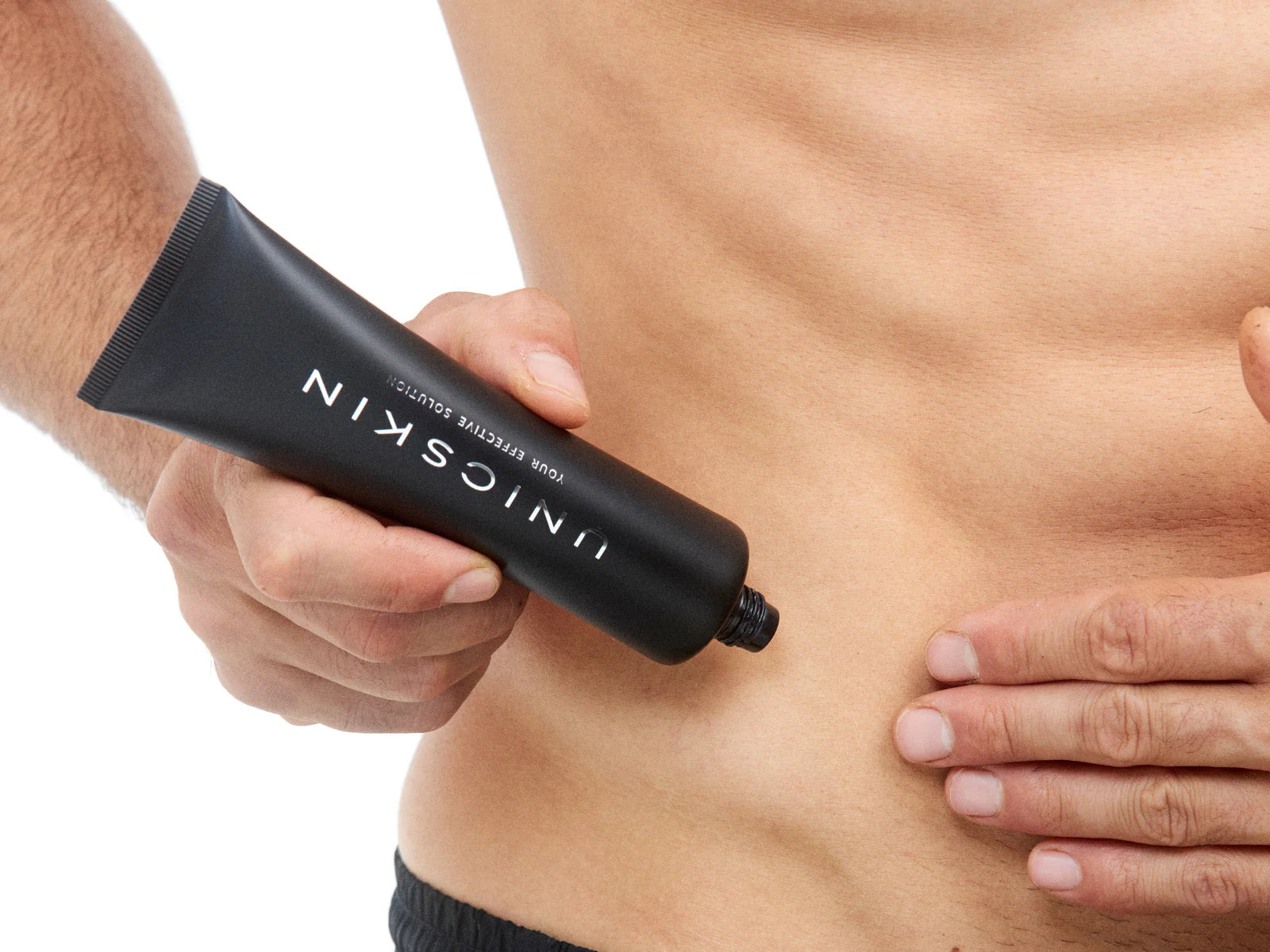 Someone applies Adverto Beauty's UNICBODY Slim Action x4 Body Contour & Shaping Cream to their bare torso, holding the sleek black tube in one hand and smoothing the firming formula onto their skin with the other.