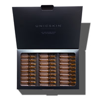 An open black box labeled "UNICSKIN" reveals rows of small brown glass ampoules inside, each with Adverto Beauty's UNIC30 Days Nighttime Detox Treatment for renewed facial skin in 30 days.